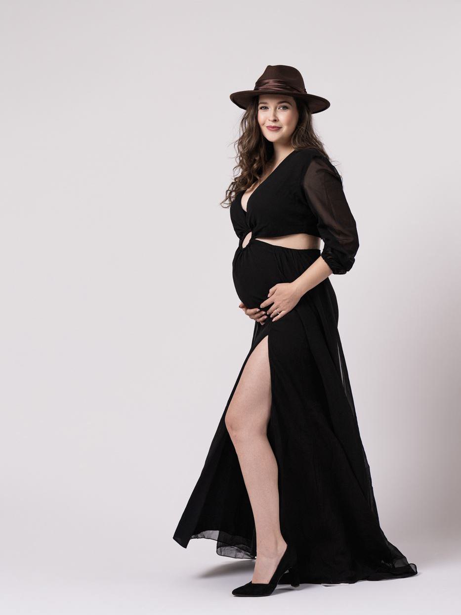 Christina mit langem Kleid und Hut zeigt, dass Schwangerschaft gezeigt werden darf.